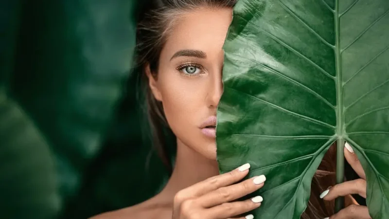Accueil - une femme tenant une grande feuille verte sur son visage