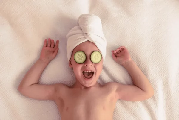 un jeune garçon avec des tranches de concombre sur les yeux pour un soin gourmand enfant - ado